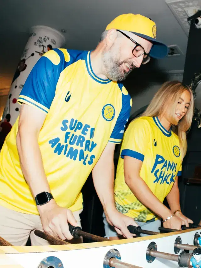 Two people at the foosball table in Super Furry Animals and Panic Shack shirts